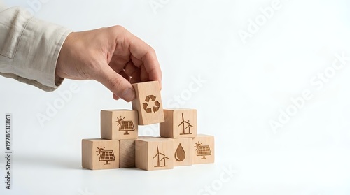 Hand placing wooden cube with recycling symbol on pyramid of eco-friendly blocks featuring renewable energy icons for sustainable business concepts.