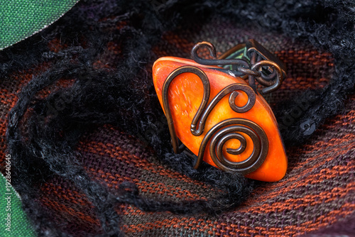 Orange stone necklace with metal detailing on fabric.