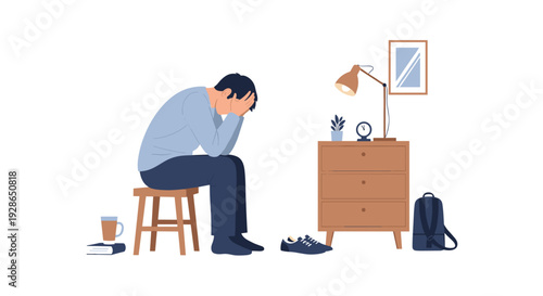 A man sits on a wooden stool with his face in his hands next to a wooden dresser with a lamp in a minimalist room.