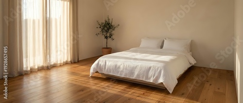 Minimalist bedroom interior with white bedding on platform bed, hardwood floors, natural lighting from large windows with curtains, and small decorative plant.