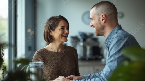 Colleagues in friendly office conversation smiling at each other in modern workspace with plants