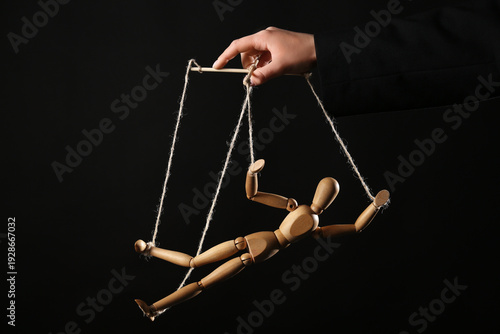 Photography Hand of puppeteer manipulating marionette on black background