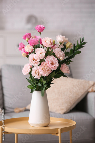 Vase with beautiful eustoma flowers on table in interior of living room, closeup