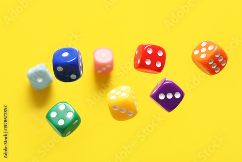 Foto Flying colorful game dices on yellow background
