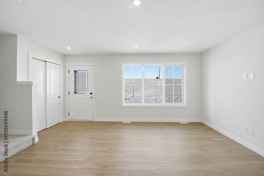 Fototapeta premium Large, empty living room with a white door and a window