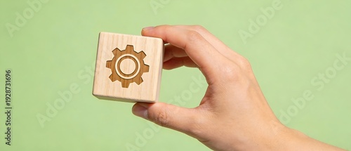 木製キューブに描かれた歯車を手で支える近代的イメージ