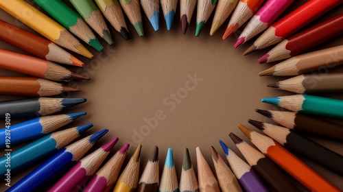 Colorful sharpened pencils arranged in circle on brown background