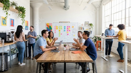 Diverse team collaborating in a modern bright open-plan office discussing ideas around a wooden table with laptops and sticky notes on a whiteboard for business concepts
