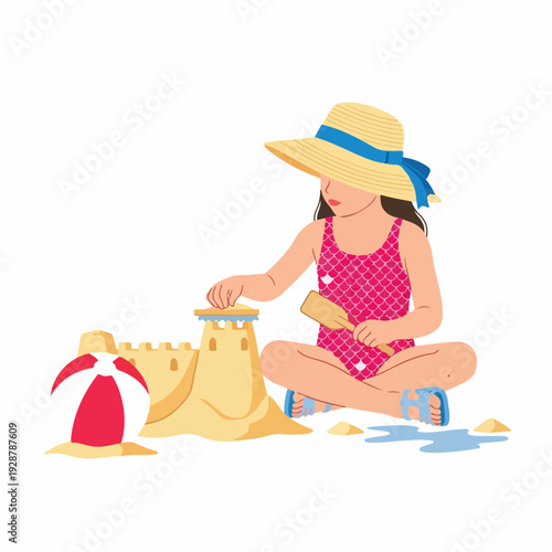 A happy little girl in a swimsuit and straw hat builds a sandcastle with a shovel on the beach, enjoying summer playtime with a colorful beach ball.