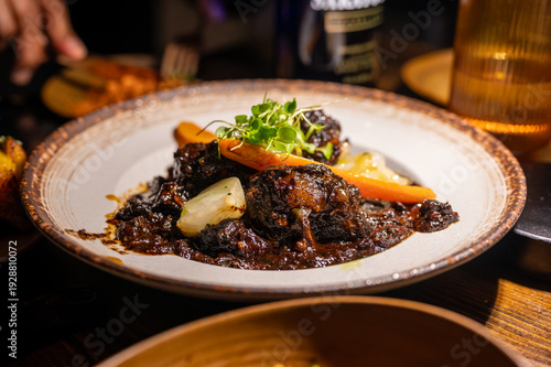 Obraz na plátne Hearty portion of dark braised meat stew with tender carrots and onions, garnish
