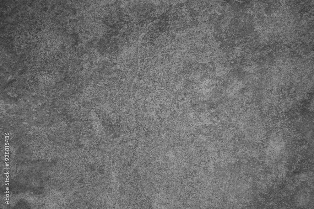 Fototapeta premium ​Gritty dark gray concrete wall texture with mottled stone surface.