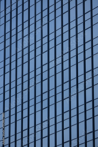 A section of a modern building with many rectangular glass windows reflecting the clear