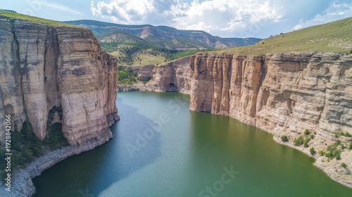 Expansive aerial view of dramatic canyon cliffs revealing a serene river below under bright daylight