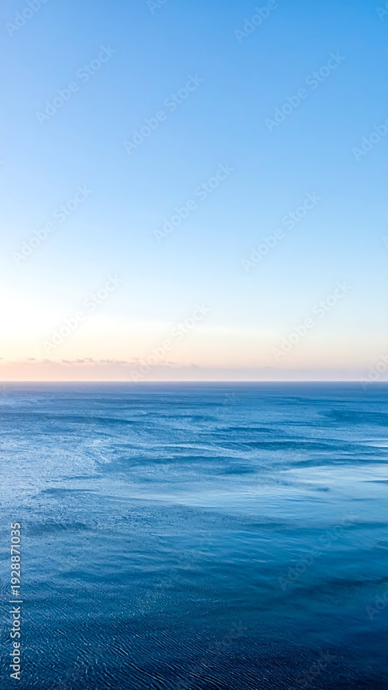 Obraz premium A serene ocean view at sunrise with calm waters and clear sky