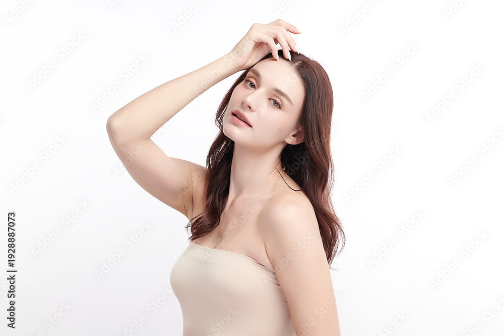 Fototapeta premium A beautiful young woman with clean, fresh skin against a white background. Skincare, facial treatment, cosmetology, beauty, and spa. An elegant portrait of an woman.