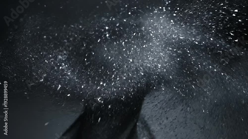 An abstract, dark image featuring a burst of white particles against a textured background