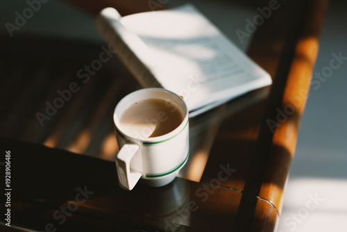 Fotografie White ceramic coffee mug with light brown beverage placed on wooden table beside