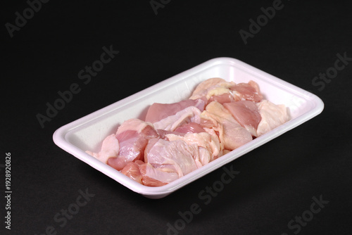 トレーに入った鶏もも肉のブロック（黒背景）