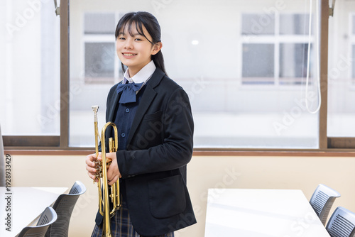Bild auf Leinwand トランペットを持って微笑む女子学生