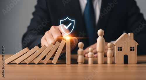 Businessman protecting family and house from falling dominoes with shield