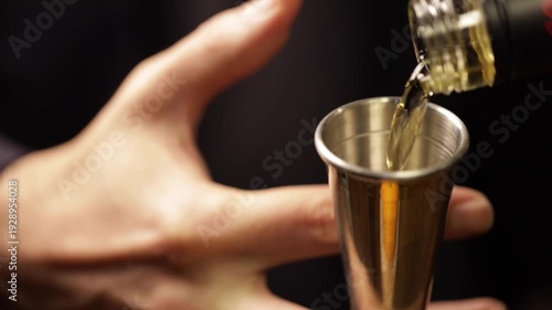Bartender pouring whiskey into a jigger. Bartender preparing an old-fashionade cocktail.
