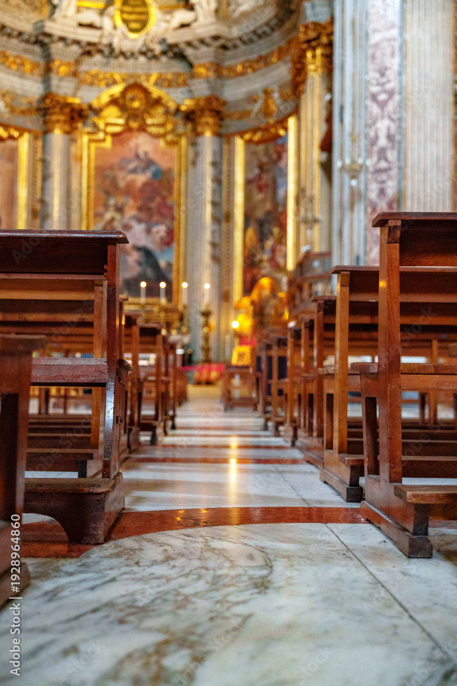 Fototapeta premium Wooden chairs line the floor in a church with ornate decorations and light coming through