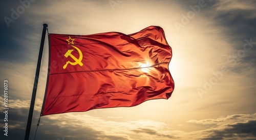 Sunlit crimson flag with golden star and hammer and sickle against dramatic sky