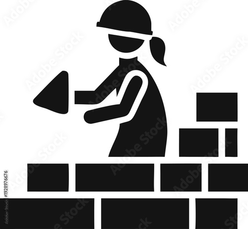 Female worker with a hardhat diligently lays bricks, constructing a new wall section