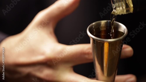 Bartender pouring bourbon whiskey into a jigger. Bartender preparing an old-fashioned refreshment.