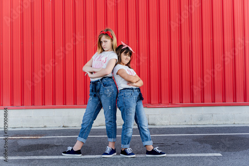 Two sisters standing in front of a red wall
