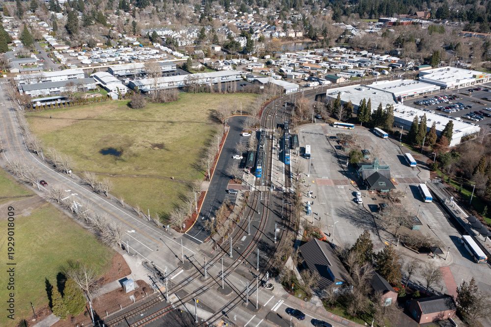 Fototapeta premium Aerial drone view of Beaverton Transit Center in Oregon USA with MAX light rail train and public buses at urban transportation hub. Rail tracks, station buildings commuter infrastructure 