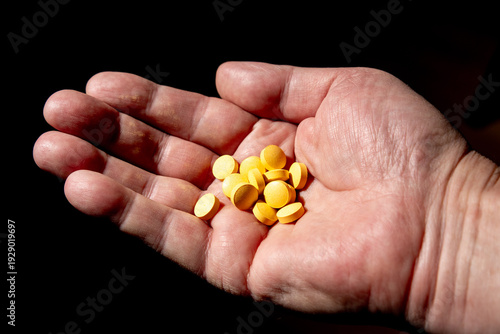Bild auf Leinwand yellow colored pills handholded on black background