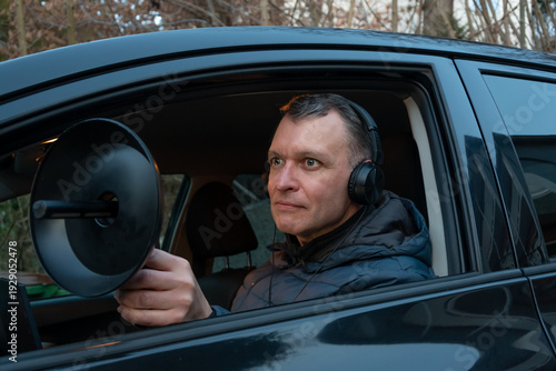 Fotografia An undercover observer records sound with a directional microphone while monitoring a target from a parked vehicle