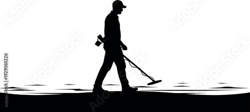 Silhouette of a man walking with a metal detector on a beach