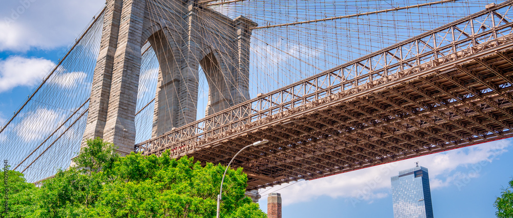 Fototapeta premium Iconic Brooklyn Bridge seen from Brooklyn Bridge Park during bright summer daylight, New York City