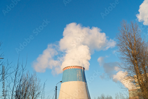 CO2, greenhouse gases emissions. CHP emissions. Smoking chimney releasing smoke against a blue sky. Smoke from factory pipe of heat station in the city. Air pollution. Nuclear power plant cooling.