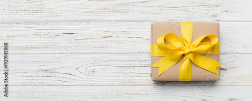 Wallpaper Mural Holiday gift box wrapped in craft paper with colored bow on table background. Top view, flat lay, copy space Torontodigital.ca