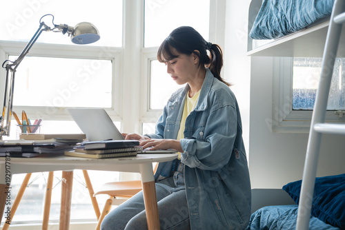 Tableau sur toile Student asian woman sitting on bed in dorm room college student Work or homework