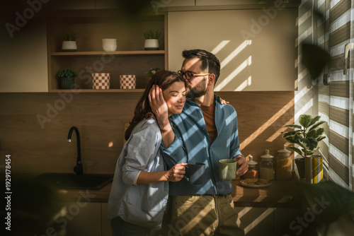 Фотография Loving couple sharing intimate morning moment in kitchen