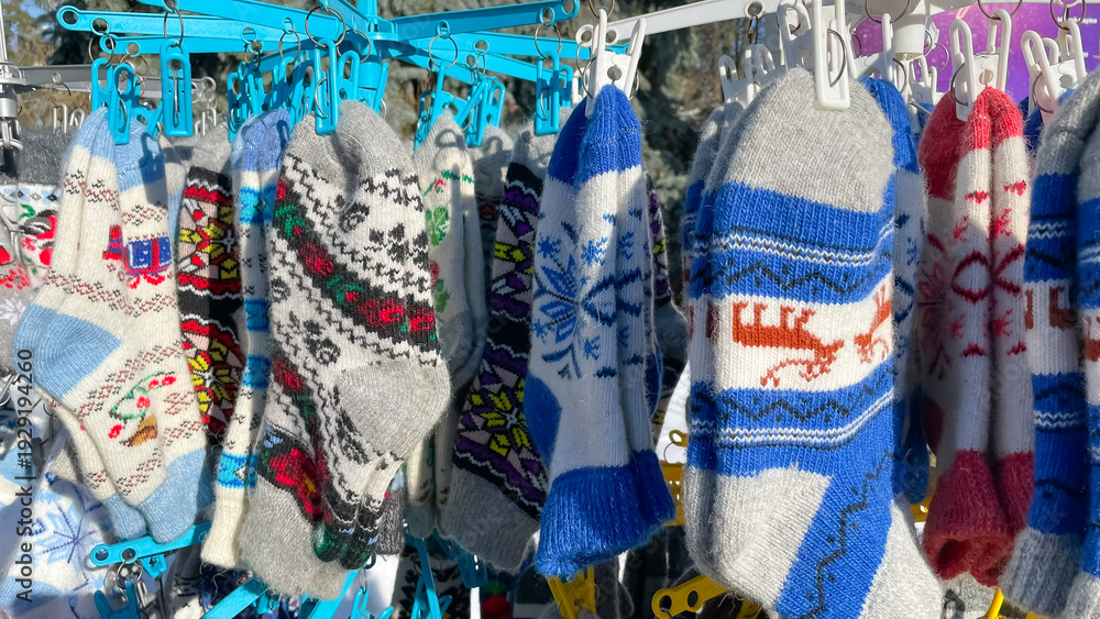 Fototapeta premium Traditional wool knitted socks with ornaments hanging at a winter street market as seasonal souvenirs.