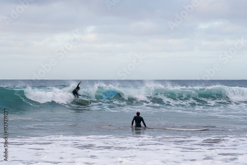 Surfer riding a breaking wave under an overcast sky