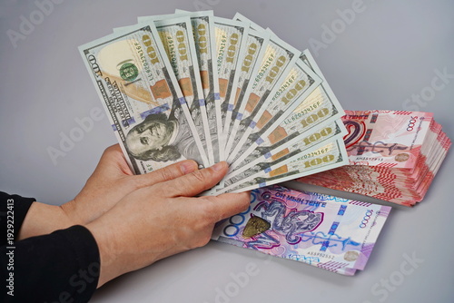 фотографія 100 dollar bills and tenge banknotes in denominations of 5,000 and 10,000 on a paper background