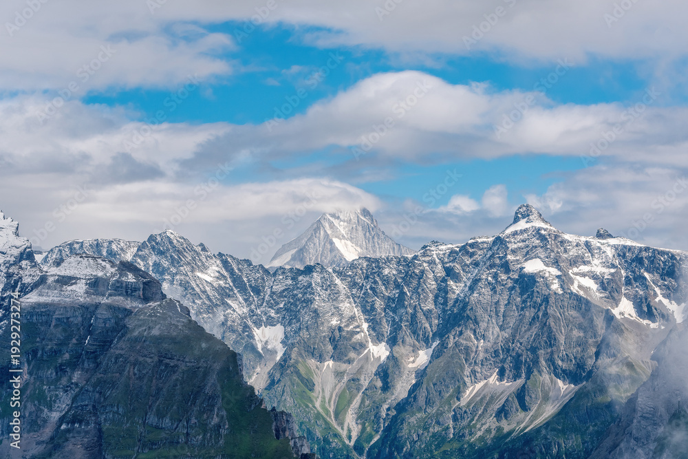 Obraz premium Majestic Peak of Mount Bietschhorn Rising Above Clouds in the Swiss Alps. View from the Via Alpina trail near Bunderspitz. 