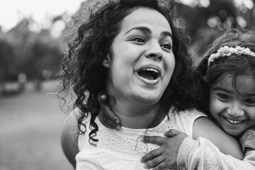 Happy indian mom having fun with her daughter outdoor - Family, mother day and love concept - Focus on mum face - Black and white editing