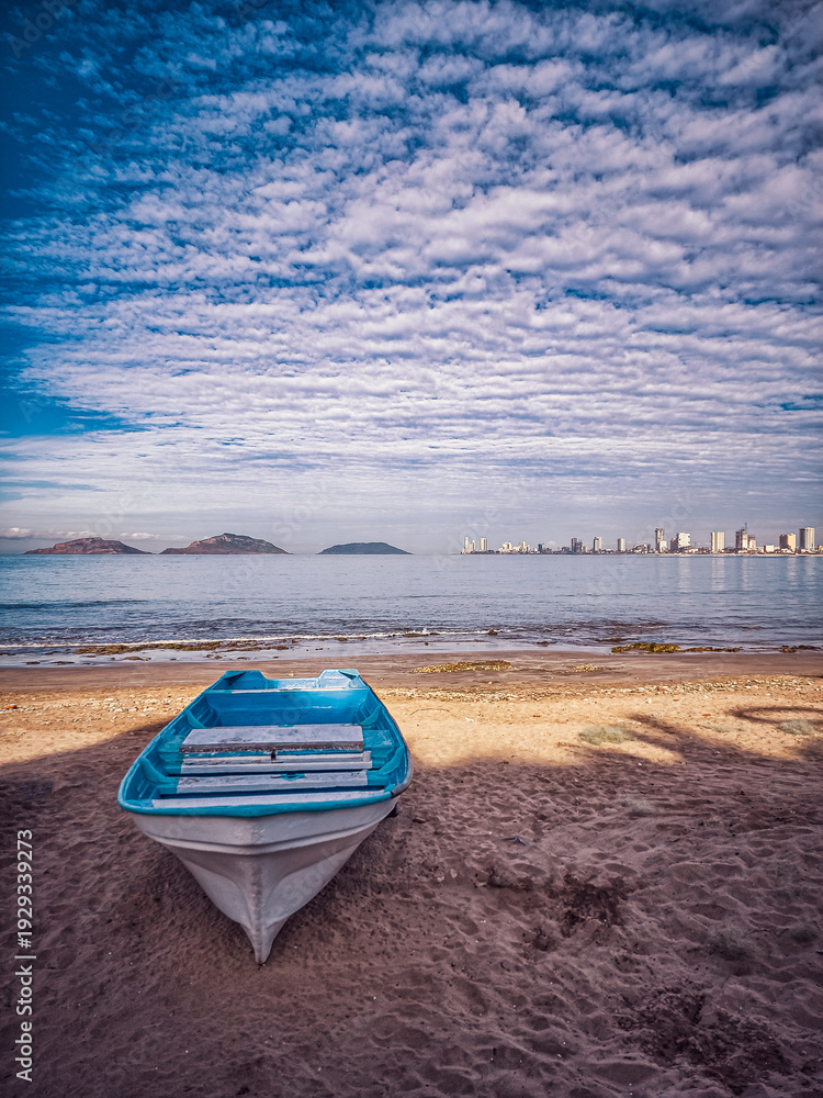 Fototapeta premium A small blue boat is sitting on the beach