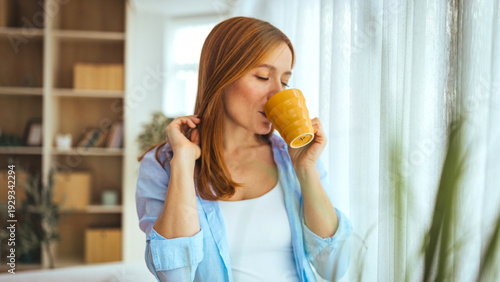 Foto Relaxed Woman Drinking Coffee At Home In Morning Light With Yellow Mug Near Wind