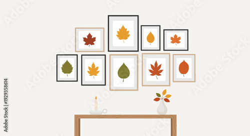 Autumn leaves in picture frames on a wall above a wooden table with a vase.