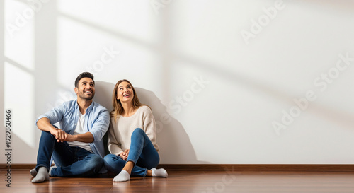 Cheerful couple sitting in an empty sunlit room perfect for moving into a new house real estate and home interior design