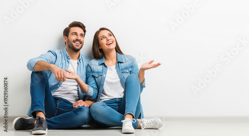Happy couple sitting on the floor pointing upwards perfect for future planning real estate decisions and family dreams