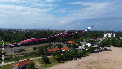 Aerial drone view of large traditional Balinese kites flying over Mertasari Beach in Denpasar, Bali, Indonesia. Colorful giant kites soaring above the sandy coastline.